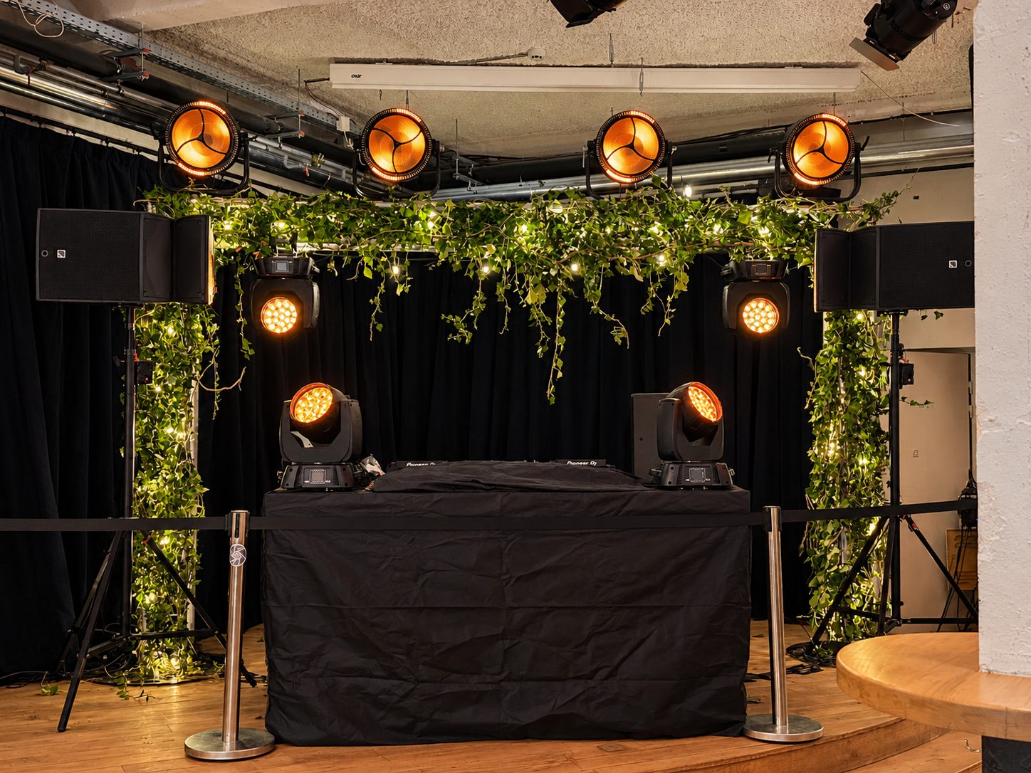 Installation DJ avec décor végétal, sonorisation et projecteurs ambrés
