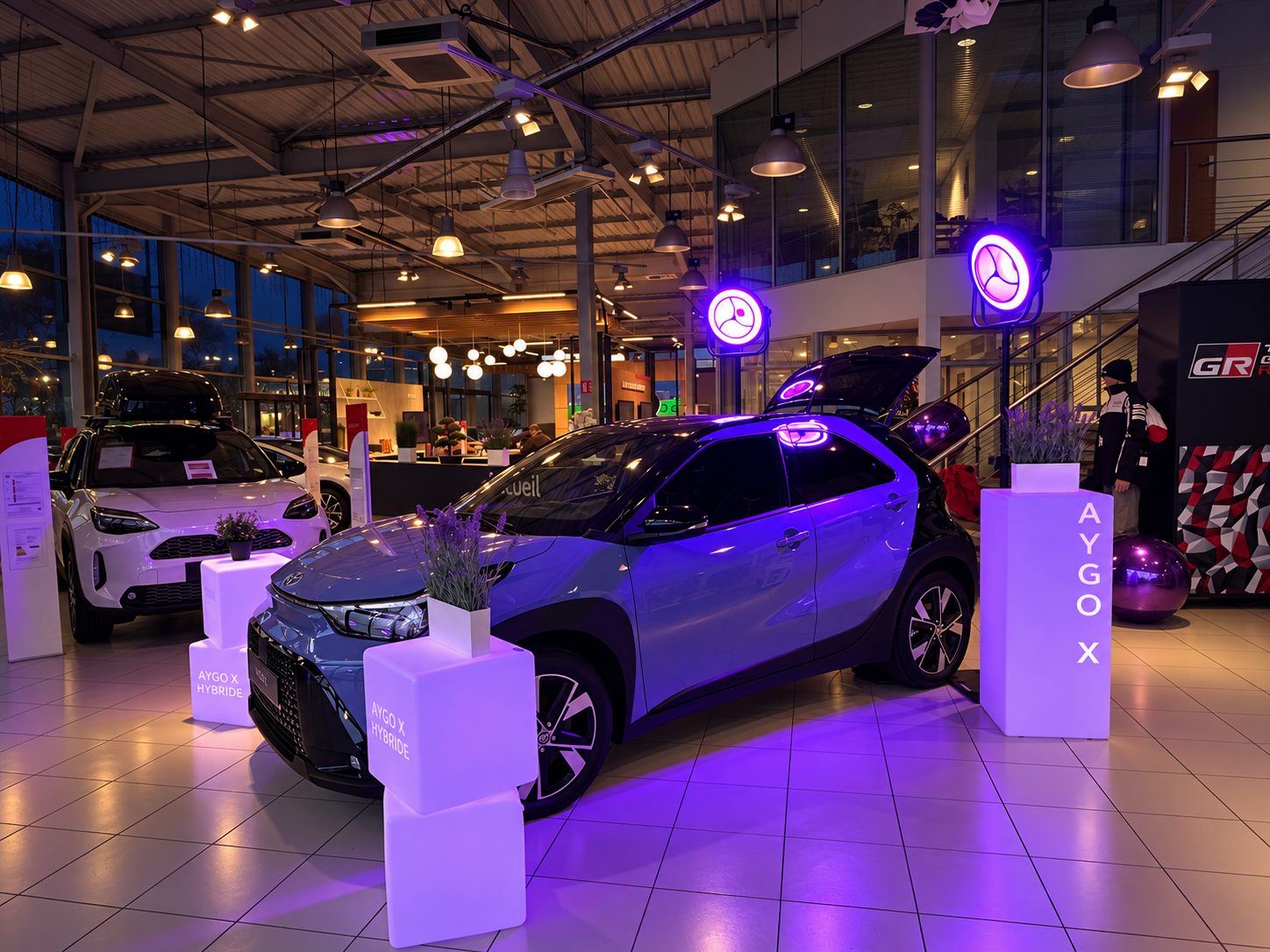Présentation d’un véhicule dans une concession avec éclairages violets et mobilier lumineux