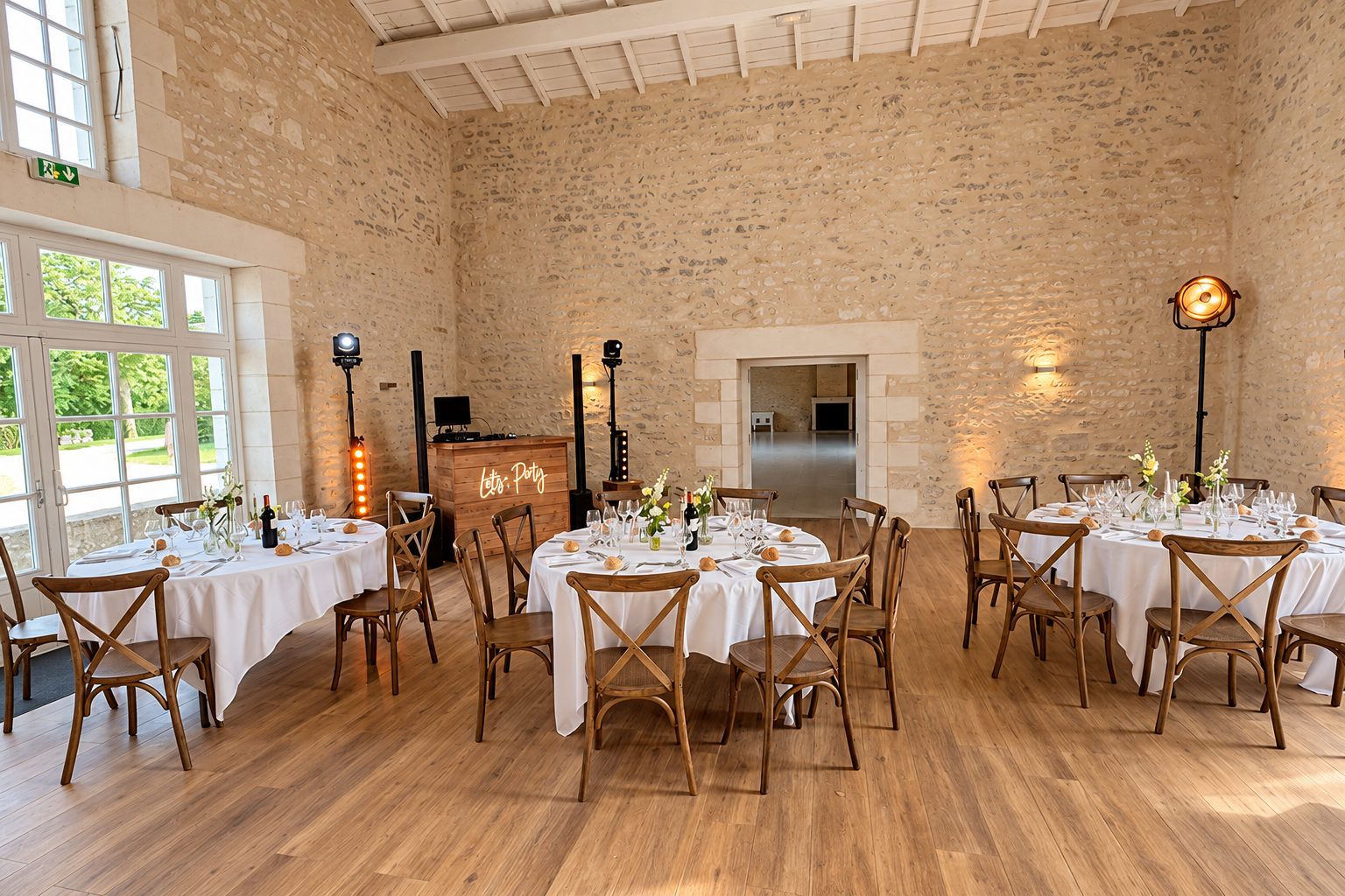 Salle de mariage en pierre avec tables rondes et installation DJ en bois