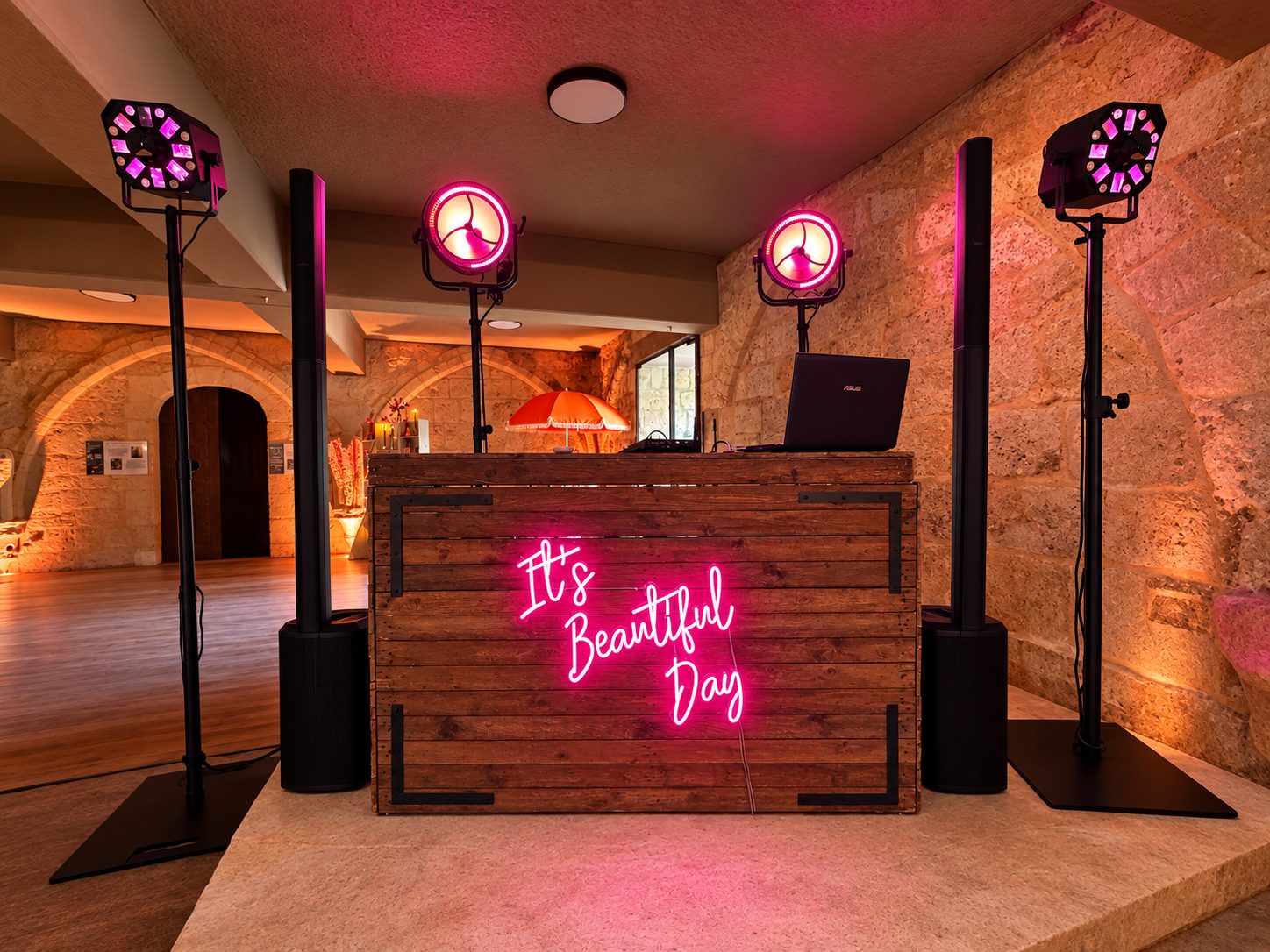 Vue de face d’un bar DJ en bois avec enseigne rose et projecteurs